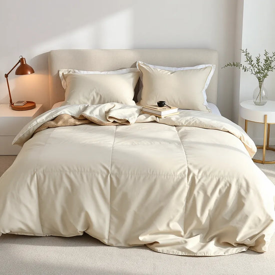 Neatly made queen bed with a coordinated bedding set, pillows, and a soft throw in natural light